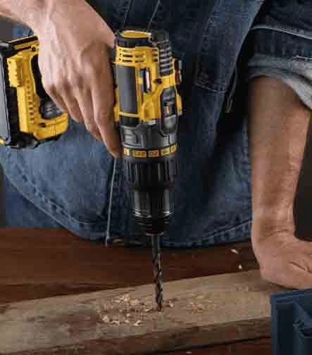 Un trabajador usando un taladro eléctrico amarillo para perforar una pieza de madera